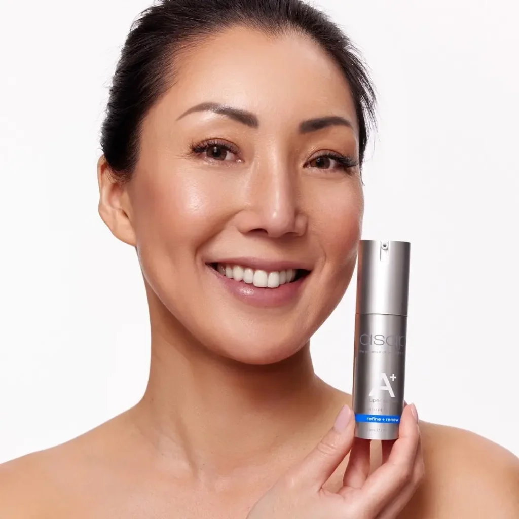 Vrouwelijke model met een glimlach houdt een flesje ASAP Super A+ Serum vast.
