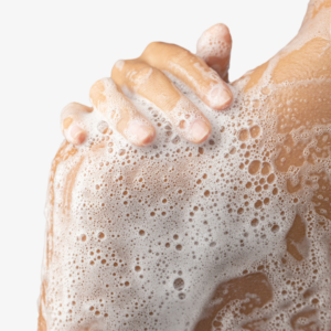 Hand op een ingezeept bovenlichaam tijdens het douchen als onderdeel van lichaamverzorging.