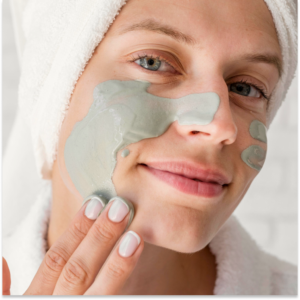 Vrouw brengt een groen gezichtsmasker aan op haar gezicht met de vingers.