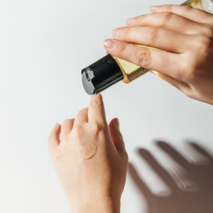 Hand die moisturizer uit een flesje op de rug van een andere hand aanbrengt.