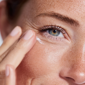 Vrouw brengt oogverzorgingscr&egrave;me aan op de huid onder haar oog.
