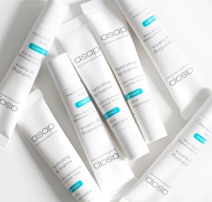 Verschillende tubes asap hydrating lip balm+ SPF15 liggen verspreid op een witte ondergrond.