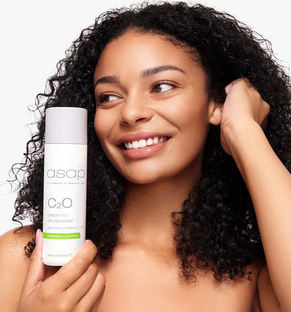 Een lachende vrouw houdt een flesje asap C20 Cleanser vast.